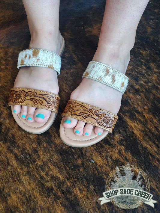 Pair of brown sandals with intricate designs on a fur surface